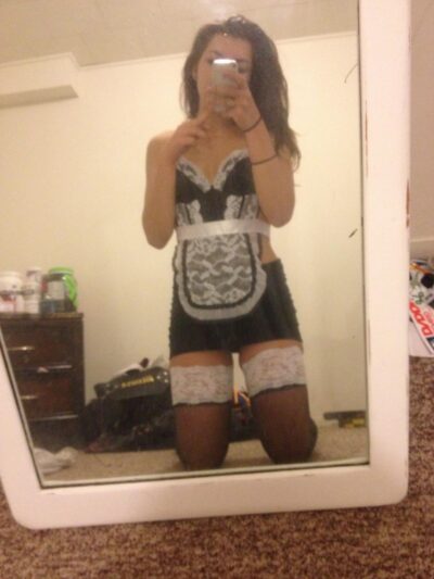 Seksowna sprzątaczka czaruje ponętnymi wdziękami. Ładna dziewczyna 20 lat w erotycznym stroju pstryka zdjęcie selfie stojąc przed lustrem.