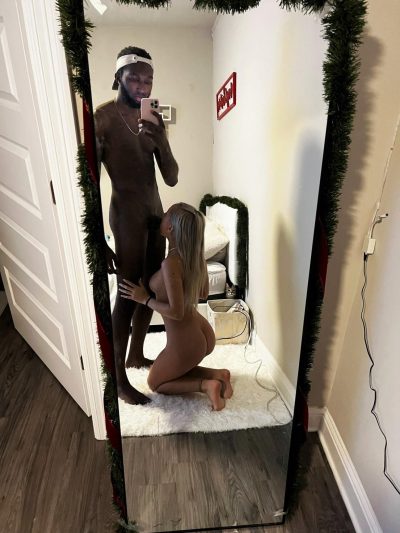 Napalona dziewczyna robi loda chłopakowi, a ten pstryka porno selfie. Blondynka delektuje się czarnym kutasem przed lustrem.